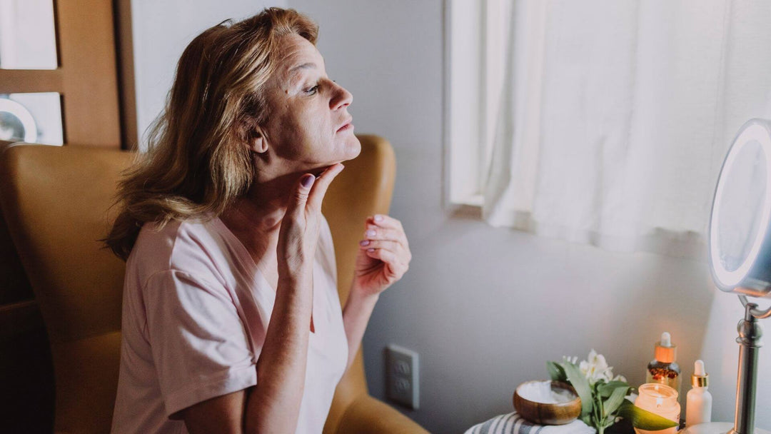 Lady sitting in her room applying CBD cream to her neck using a mirror